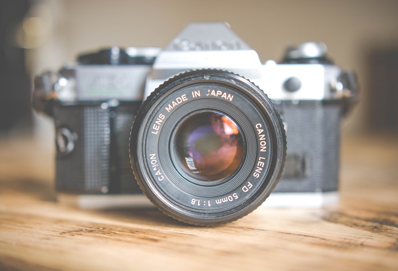 canon lens on a vintage canon camera on a wooden surface, vintage canon camera on wooden table 4k