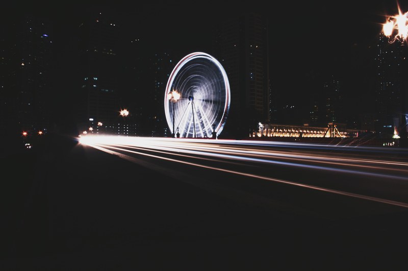 long exposure photo of ferris wheel and traffic lights in downtown area, spinning light 4k