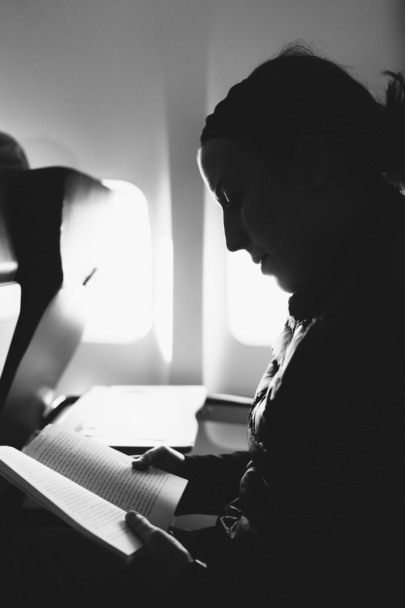 black and white shot of man reading book in aeroplane, man reading book in plane 4k