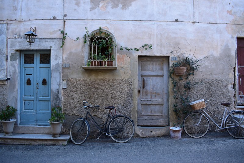 two bicycles parked near wooden doors in an old building facade, wall 4k