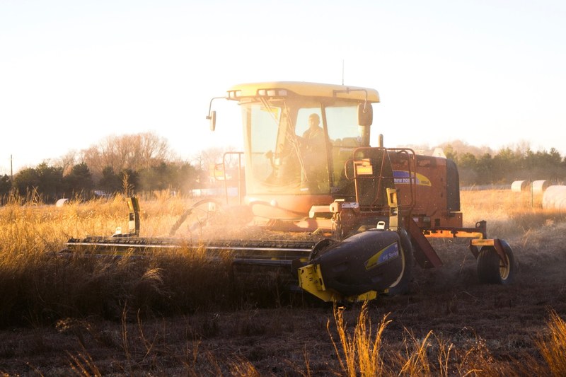 a farmer in a tractor clearing wheat during sunset in lincoln, sunset harvest 4k