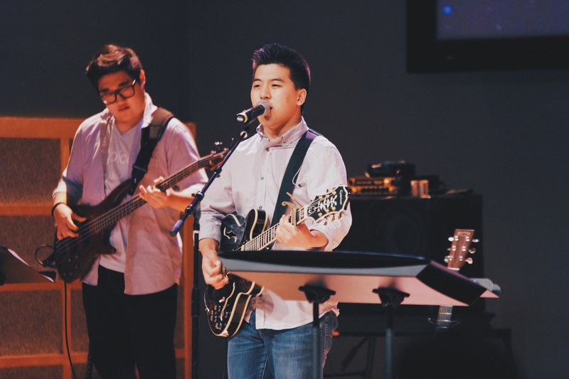 a young man playing the guitar and singing into a microphone during a live performance, young band performing 4k