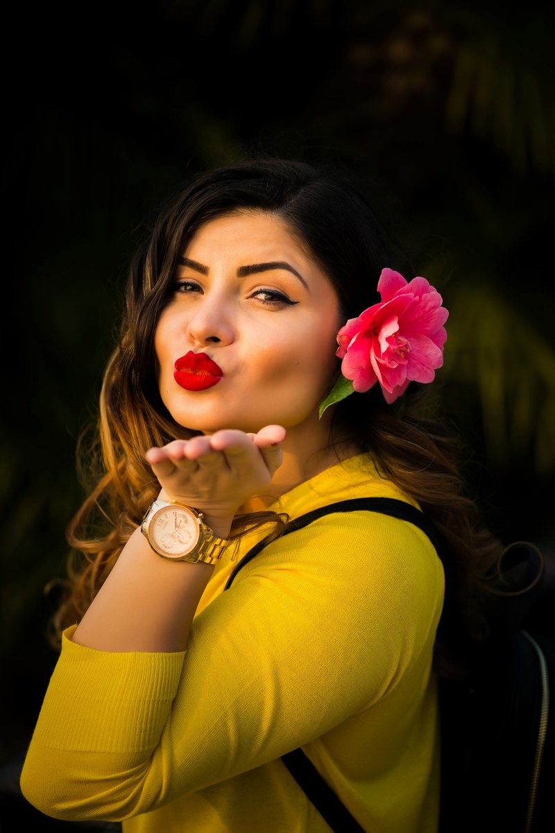 a woman with a pink flower in her hair blowing a kiss towards the camera, blowing a kiss 4k