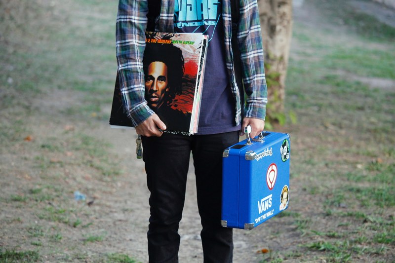 a person carrying a blue case and stack of records including one by bob marley, bob 4k