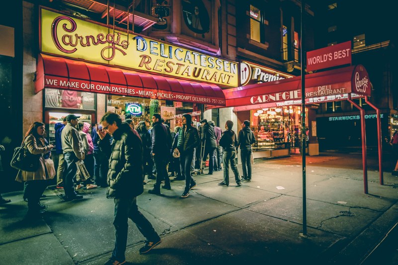 a man walking by a busy carnegies delicatessen restaurant location in new york city, busy new york city restaurant 4k