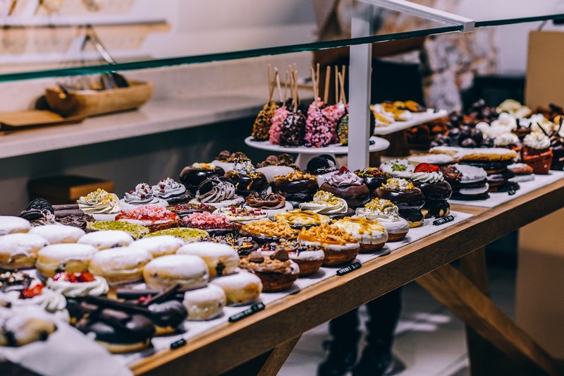 donuts and various pastries with colorful glazing on a display shelf, spanish pastries 4k