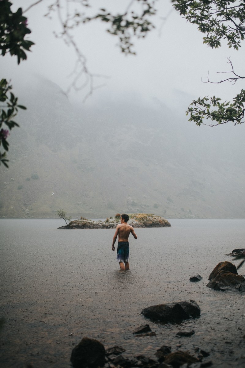 man walks into a lake on a foggy day in lake district national park, foggy swim 4k