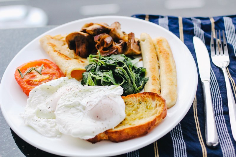 hearty breakfast with eggs toast tomato and vegetables, table of food and cutlery 4k