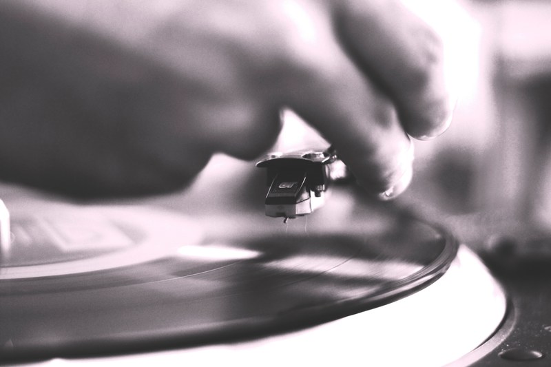 unfocused black and white shot of hand putting needle on a record on a turntable, visit to the vinyl shop 4k