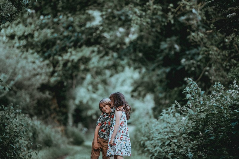 two young children a boy and girl hug outdoors in a green forested area, siblings children hugging_ 4k
