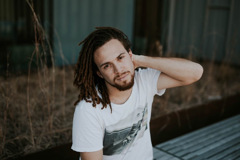 man with dreadlocks pushes smiles and pushes to the side, shy smiles 4k