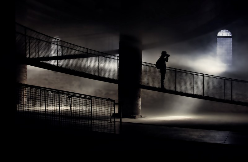 a silhouette of a photographer on a dark staircase in an old building, the photographer in the fog 4k