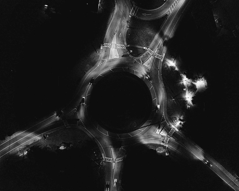 a dim drone shot of a traffic circle illuminated by streetlights, dark traffic circle from above 4k