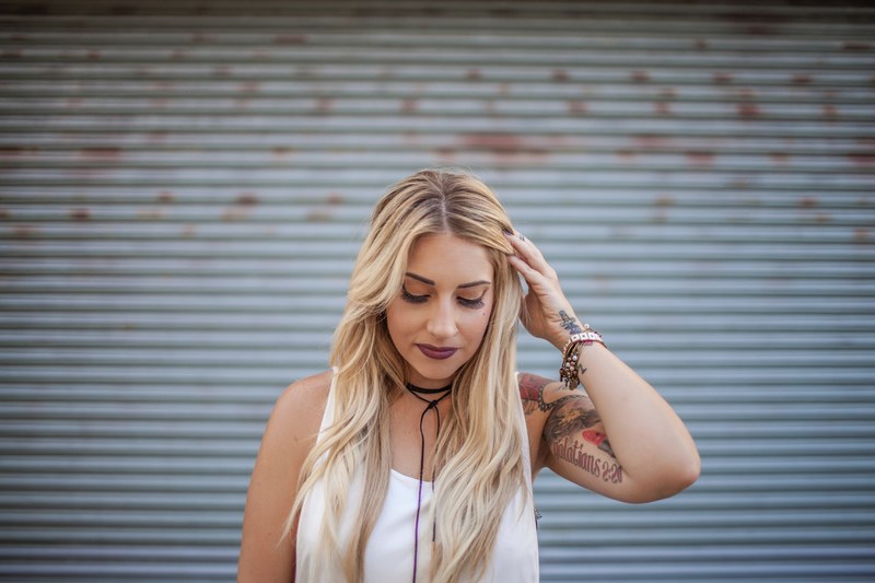 happy woman with a tattoo fixes her hair and looks down, cassandra 4k