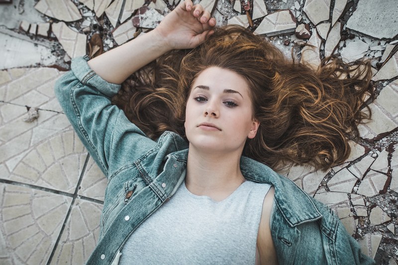 woman with a neutral expression lying down with her hair splayed out, splayed out hair 4k