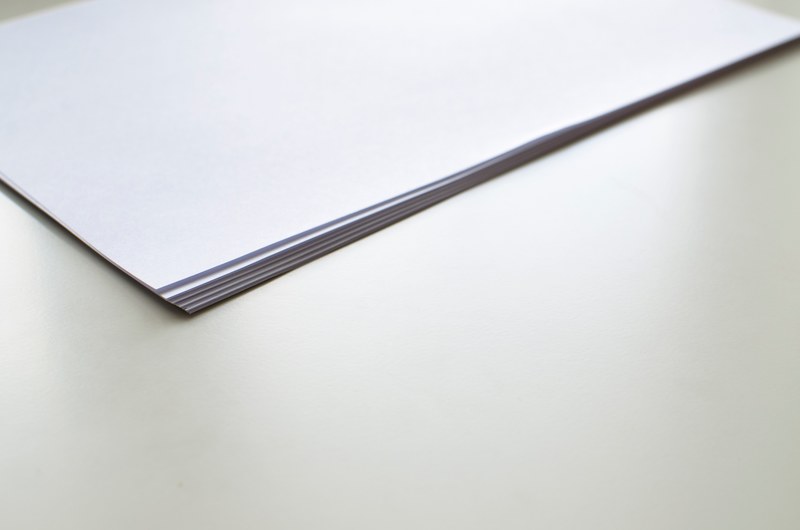 a stack of white paper sheets on a white surface, office situation with paper on white table 4k