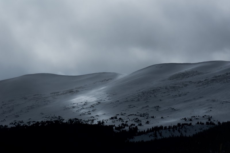 a snow covered hillside under thick gray clouds, gray hillside 4k