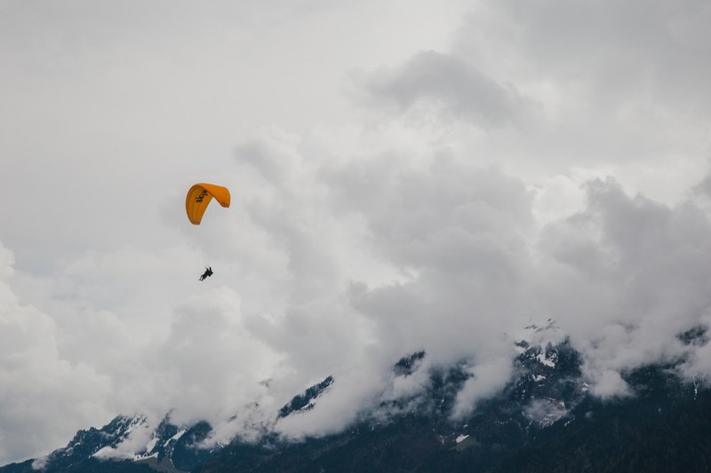 person with a yellow parachute paragliding in the clouds, paragliding interlaken switzerland 4k