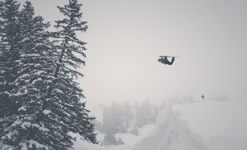 a drone flying in the snow along a tree line in black and white, black and white drone flying in snow 4k
