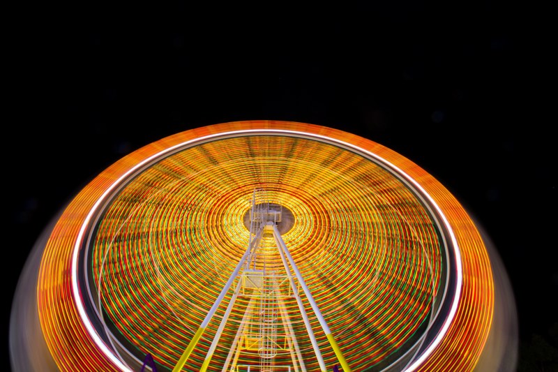 a time exposure shot of a ferris wheel with vivid orange and yellow light trails, orange and yellow ferris wheel light trails 4k