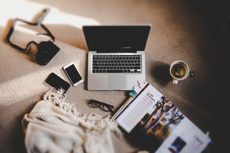 an overhead shot of a laptop a book a cup of tea and a blanket on a carpet, round the world trip planning 4k