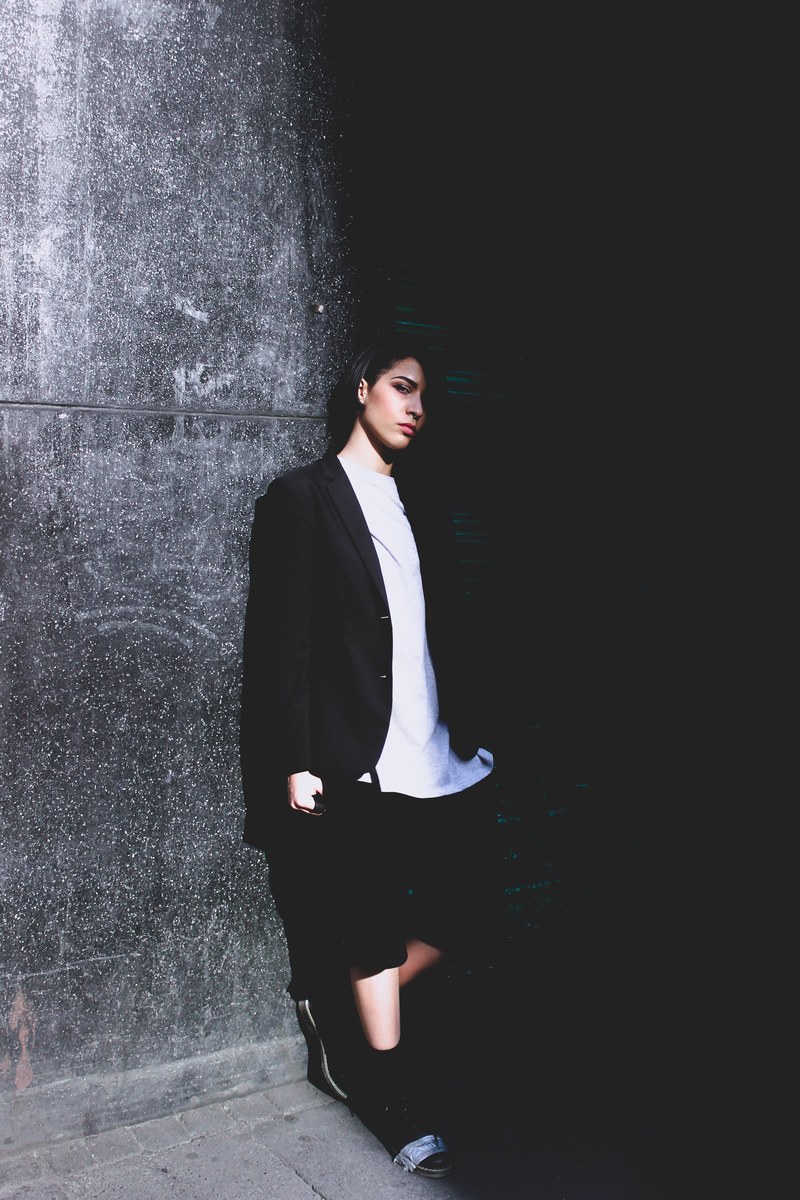 person in business casual clothes leaning against a wall in partial shadow, inception 4k