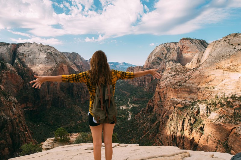 a woman with her arms spread out on top of a mountain, _angels landing 4k