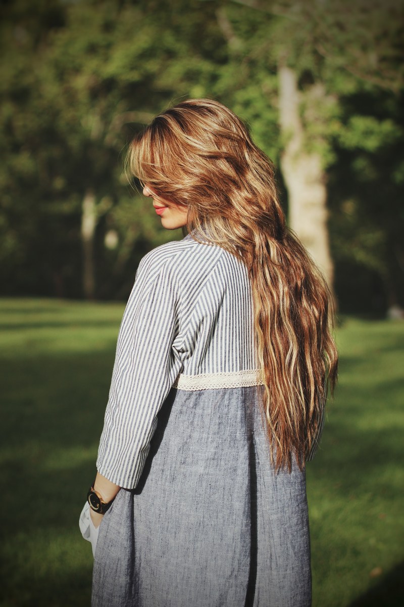 a woman in a dress with long blonde hair obscuring her face in a green park, woman with hair obscuring face 4k