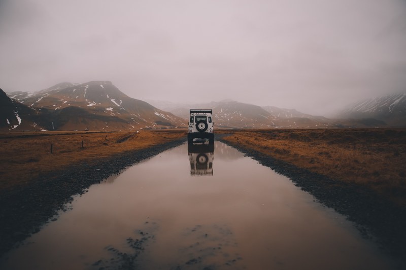 white offroad landrover in a foggy skgar region reflected in a puddle of water, land rover in a foggy skgar region 4k