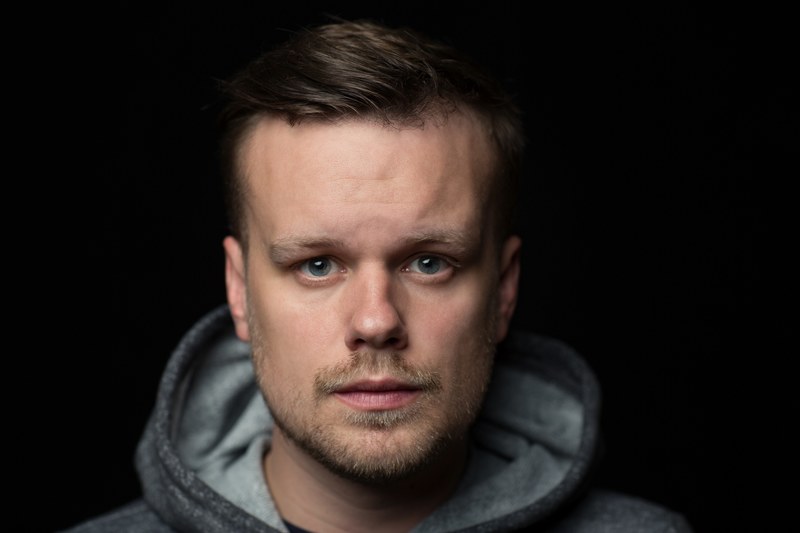 a bearded man in a hoodie looks directly at the camera against a black background, bearded man in hoodie 4k