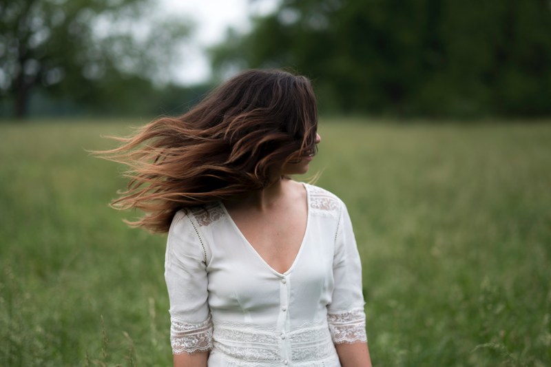 woman in a white shirt with windblown hair in a field, move 4k