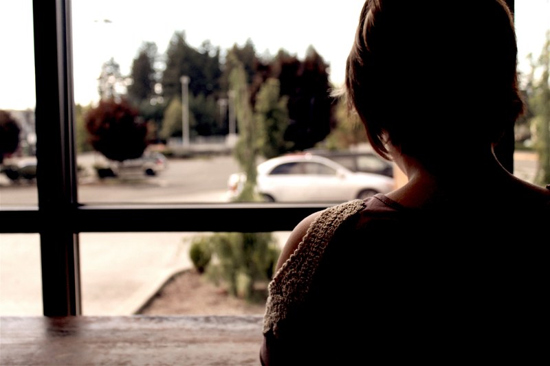 person sitting at a cafe ledge looking out the window, view from the window 4k