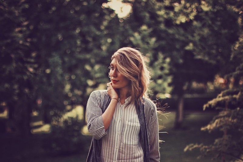 a woman wearing a striped shirt smiles to the side in front of trees, striped shirt woman with trees 4k