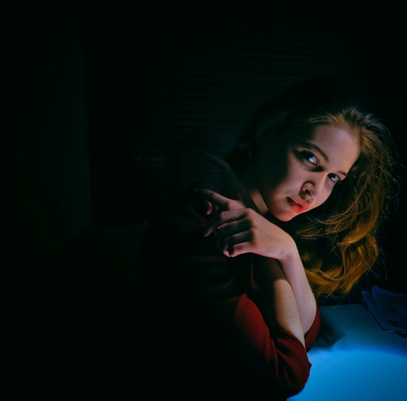 young woman leans forward with arms wrapped up in the shadows, night beauty 4k