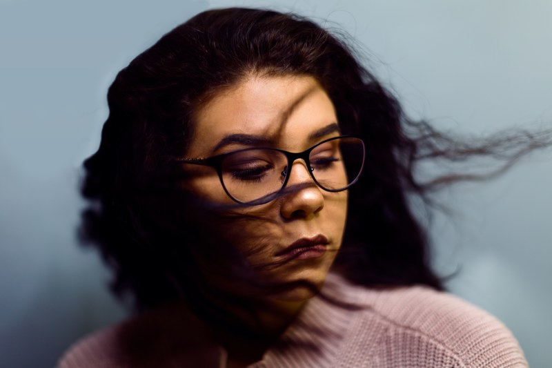 serious woman in glasses shaking out curly hair, wind blown hair 4k