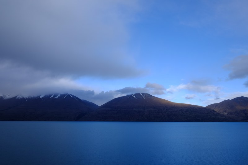 the calm surface of lake ohau by a mountain range under clouds, lake ohau under thick clouds 4k