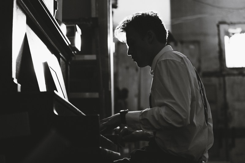 a black and white shot of a man in a white shirt playing the piano, play for me 4k