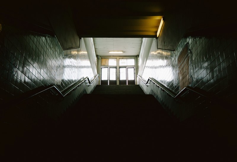 dark stairwell with light at the top, dark staircase with sun lit doors 4k