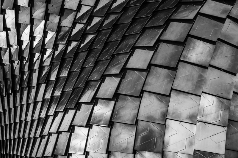 black and white shot of undulating patterned architecture with reflection metropolitan city of milan, building scales 4k