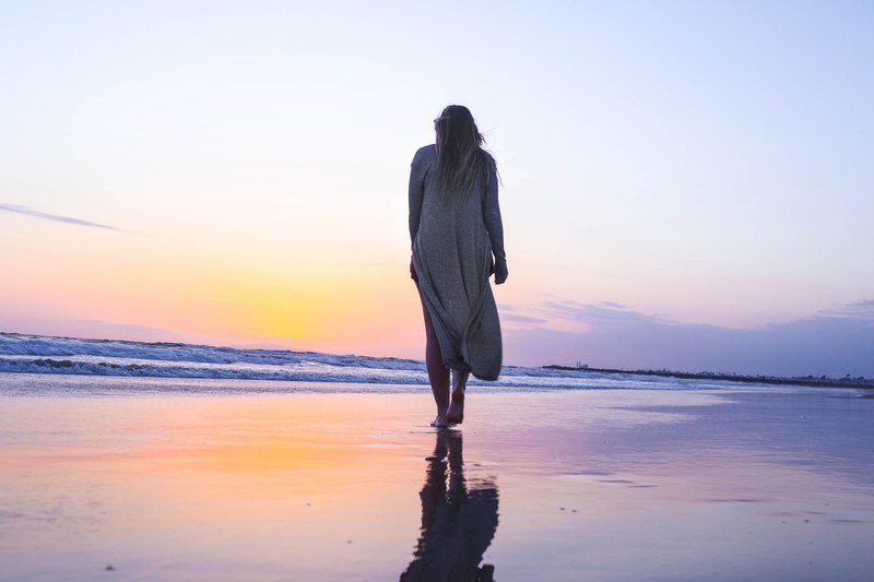 woman walking on a wet sand beach towards the sunset at newport beach, woman walking on sand beach 4k