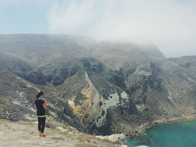 woman looks out at mountain view over the sea, taking in the scenery 4k