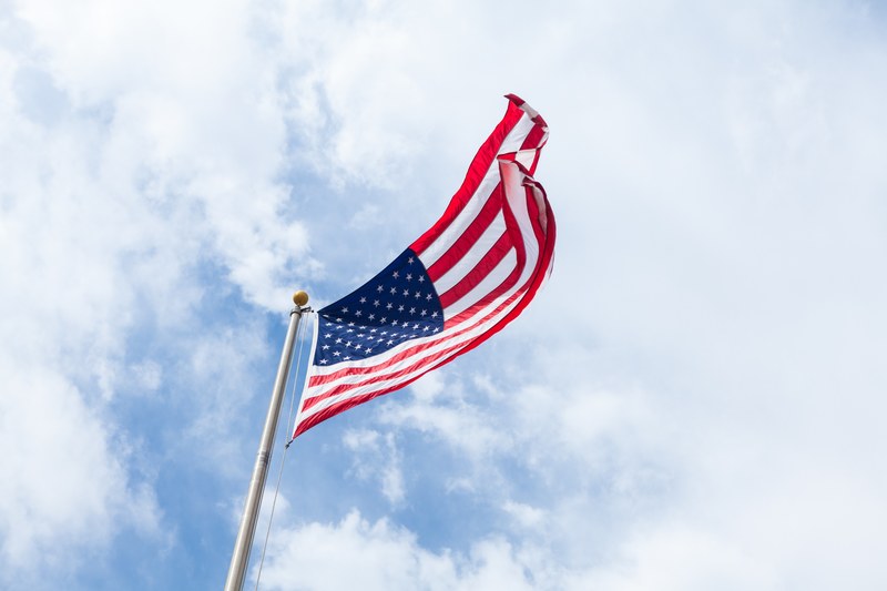 an american flag flies in the wind atop a flagpole, patriotic american flag 4k