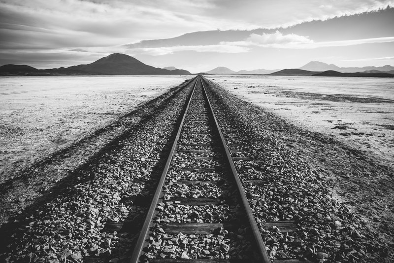 a black and white shot of a railway track through a barren wilderness in bolivia, railway track to nowhere 4k