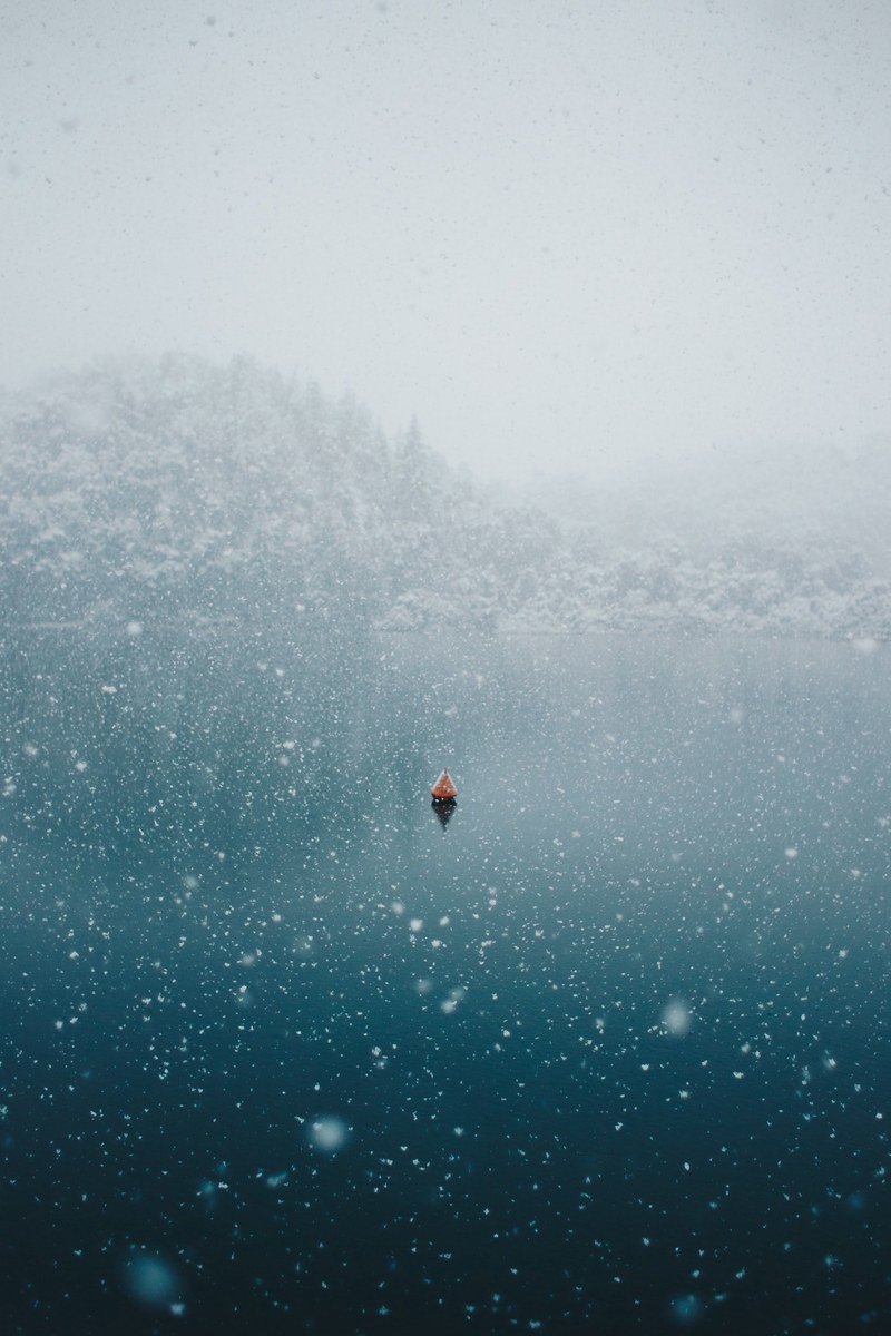 snowing over an ocean with a lone boat, _patagonian lake buoy 4k