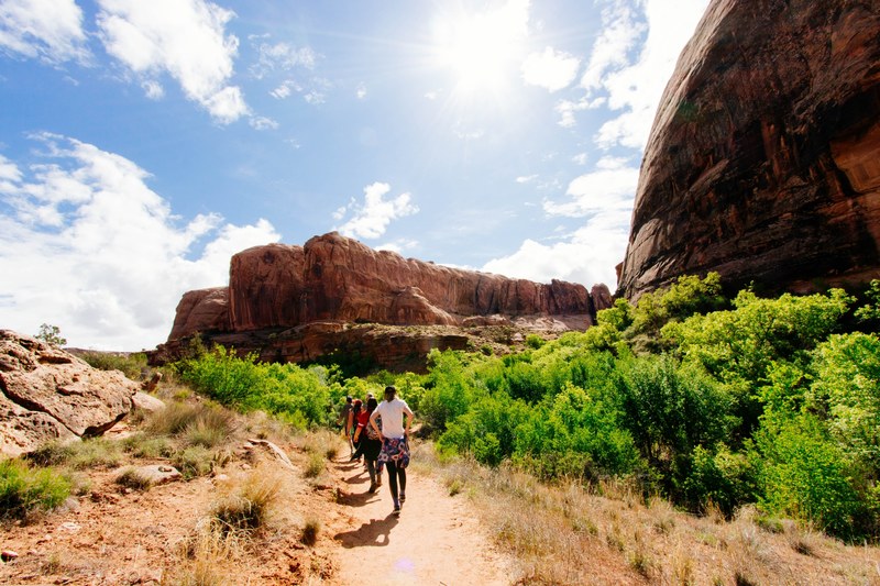 hikers walk along a desert path toward a rocky mountain ridge, group adventures 4k
