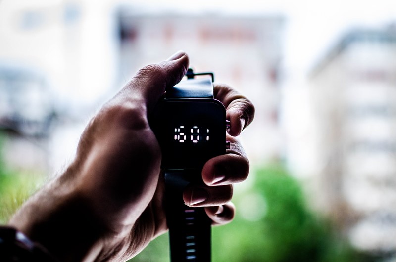 a persons hand holding a digital watch displaying the time, time is money 4k