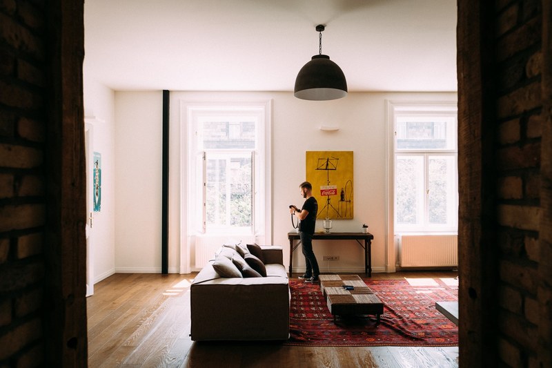 man stands in bright living room near couch and low table in front of poster, flat in budapest 4k