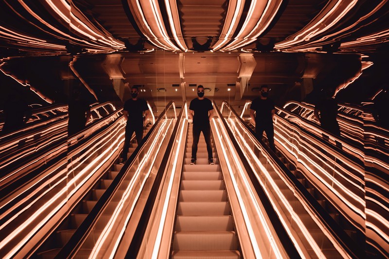 mirrors form a creepy optical illusion of a man going down an escalator, seeing double making triple seeing quadruple 4k