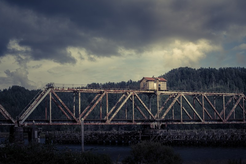 a small old building on top of a steel bridge over a river, abandoned building on a bridge 4k