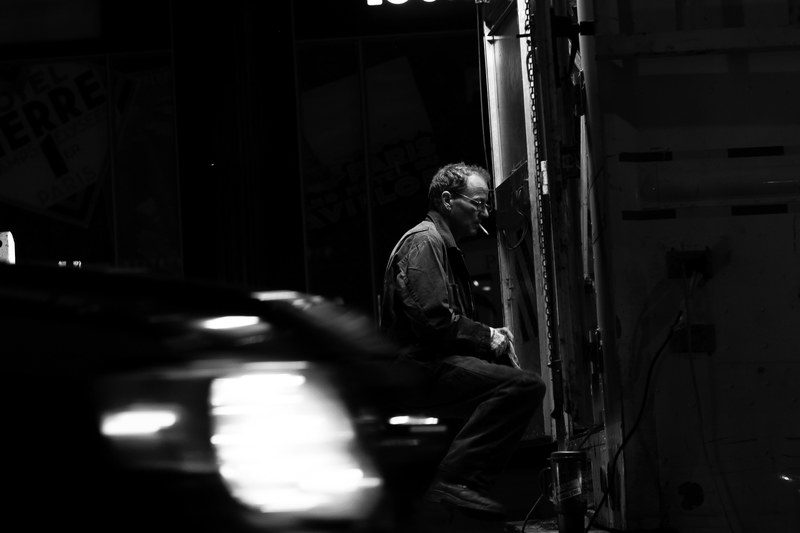 a man in black and white sits operating a machine against a blurry background, on the job 4k